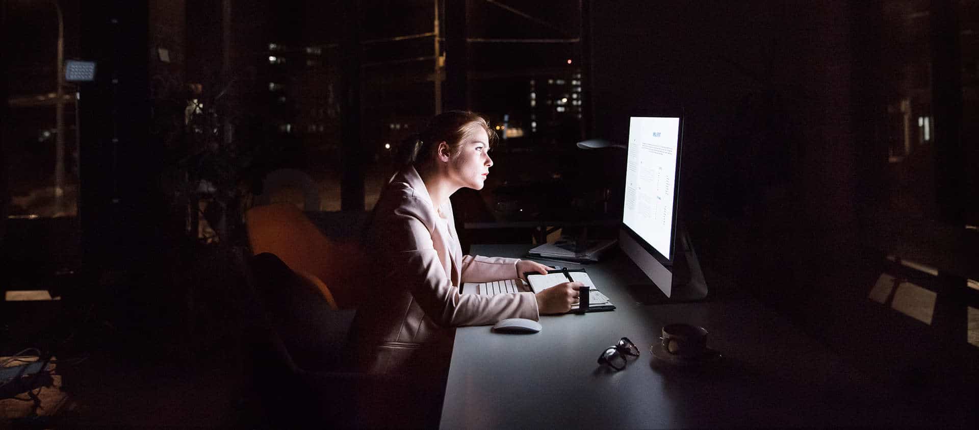 Businesswoman in front of computer screen in office at night