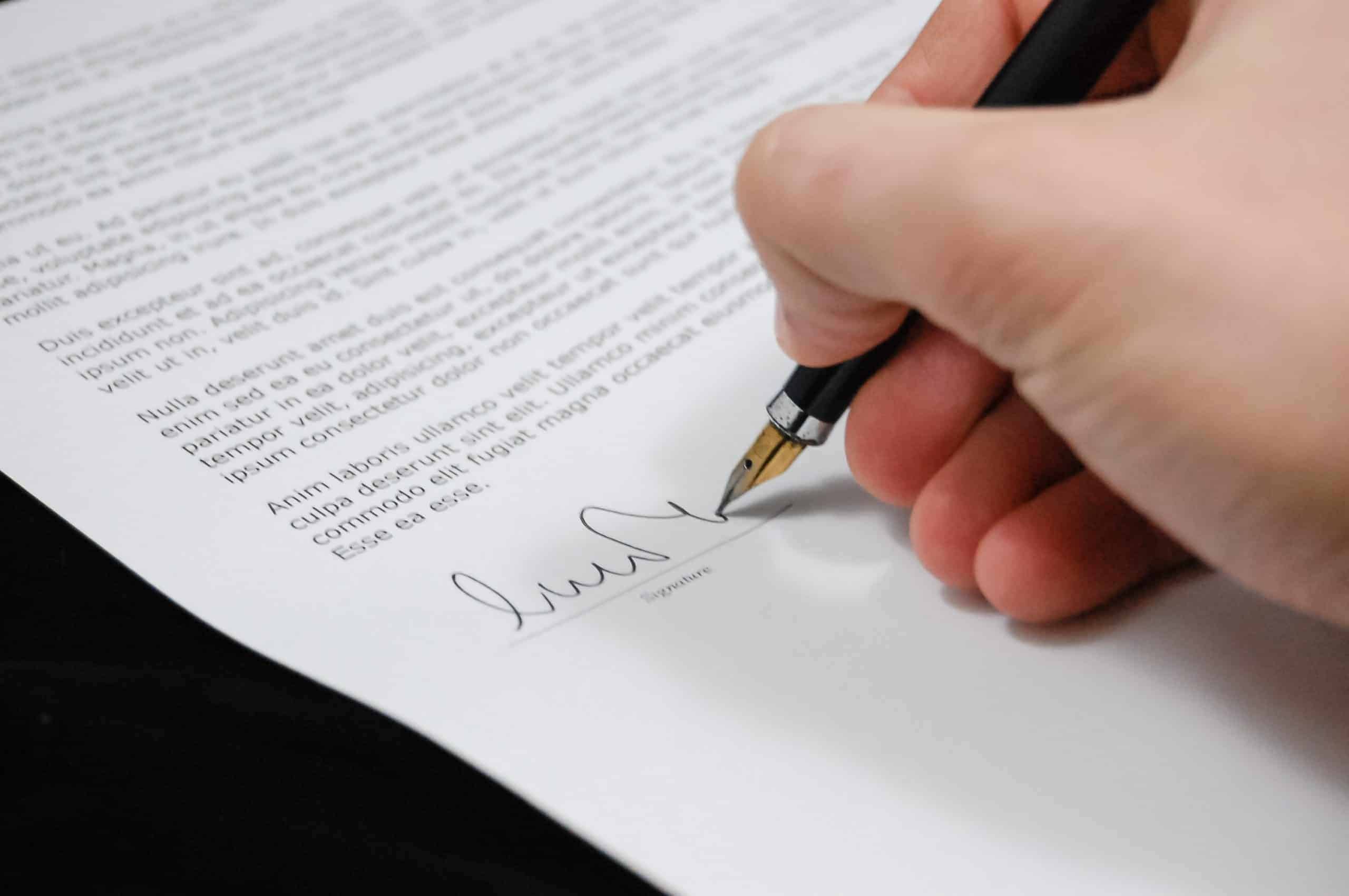 person using pen to sign document