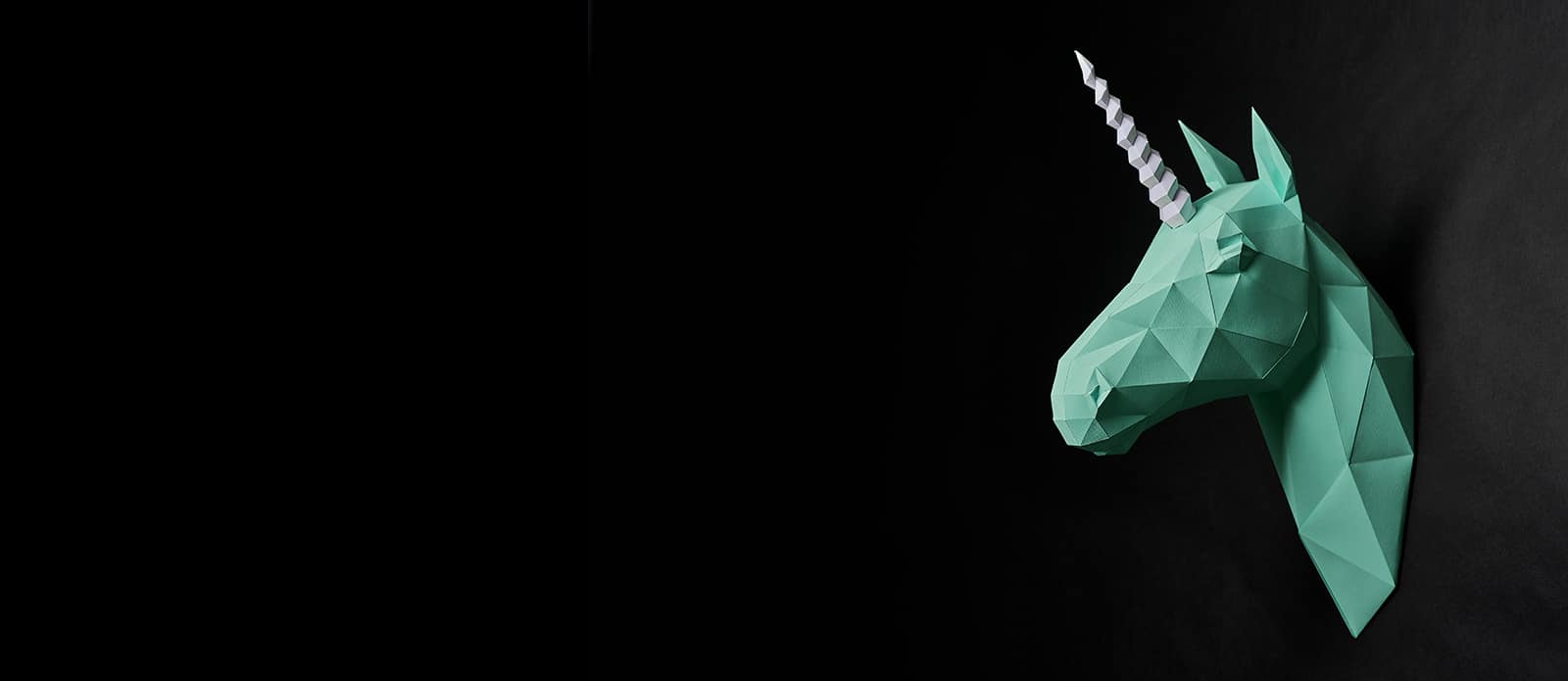 Origami Dull Green Unicorn's Head Hanging On Black Wall.