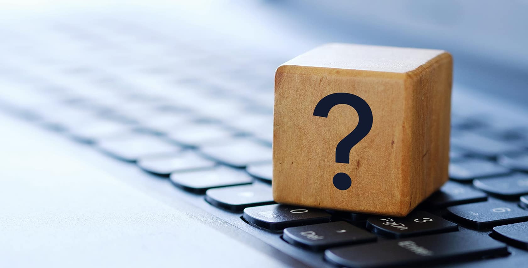 a question mark on a wooden cube on a computer keyboard