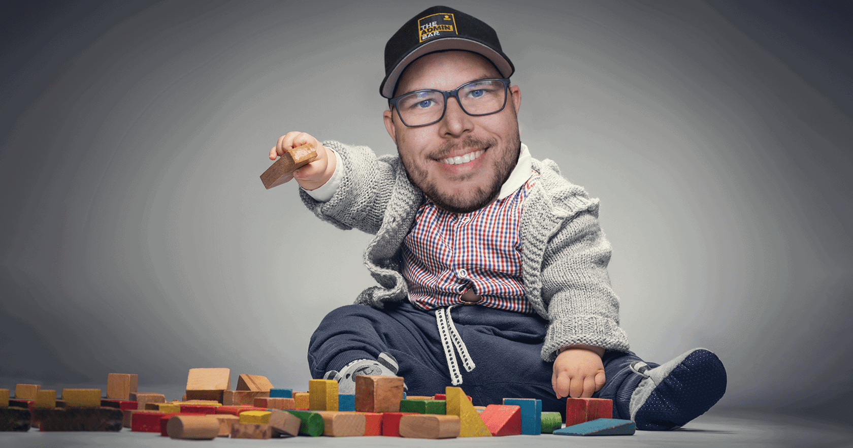 a baby sitting up playing with blocks with Kyle Van Deusen's head superimposed on the baby