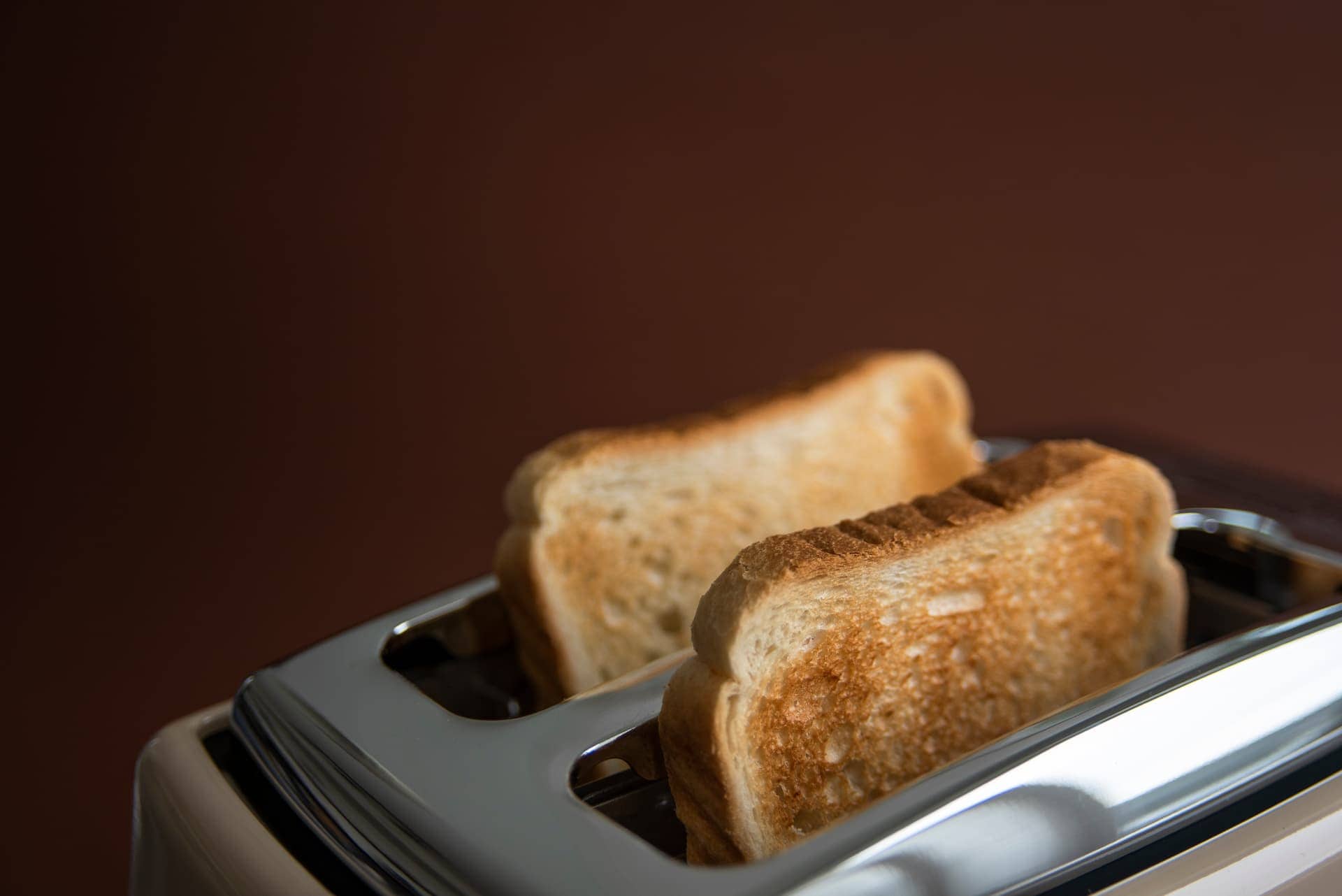 Toaster with two toasted bread slices ready to serve, close-up photo for breakfast or kitchen themes.