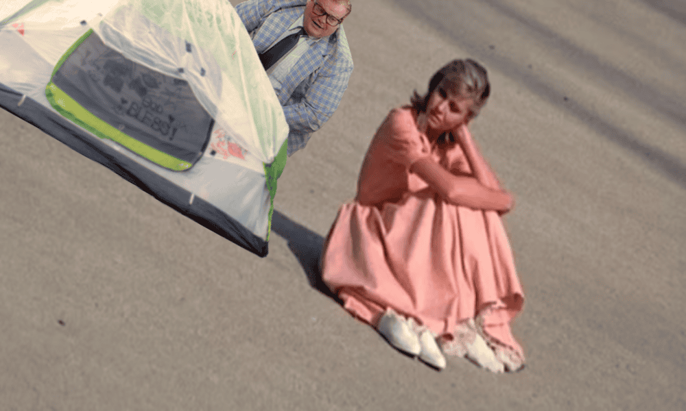 Woman sitting on the street with a tent nearby, looking thoughtful.